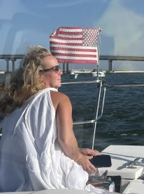 A woman enjoys a serene moment on a boat, with the American flag waving in the background — a perfect snapshot of a relaxing day on the water.