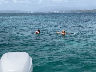 A couple enjoys a refreshing swim in the clear ocean waters, showcasing the perfect blend of relaxation and adventure during their boating experience.