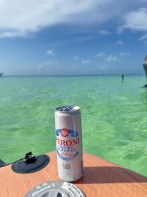 A refreshing Peroni beer sits on the deck, surrounded by crystal-clear waters, perfect for enjoying a day on the boat.