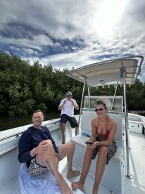 A group of friends relaxes on a boat, enjoying a sunny day surrounded by lush mangroves — perfect for a fun day on the water.