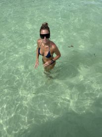 A woman enjoys a refreshing swim in crystal-clear waters, showcasing the perfect beach day experience.