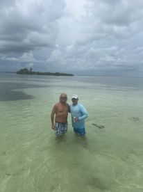 Two friends enjoy a refreshing swim in shallow waters near an island, capturing the essence of a perfect beach day adventure.