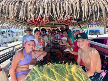 A lively group of family and friends enjoys drinks at a tropical bar, capturing the essence of fun and celebration during their boating adventure.
