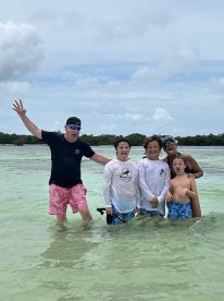 A lively group of family members enjoys a fun day in the water, showcasing their playful spirit while swimming in a beautiful tropical setting.