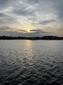 A serene sunset over calm waters, showcasing the beautiful coastline — perfect for peaceful evening boat rides.
