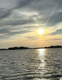 A serene sunset over tranquil waters, reflecting golden hues and showcasing a distant island — a perfect backdrop for peaceful boating experiences.