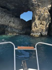 A stunning view of a natural rock formation with a hole, seen from the bow of a boat — a perfect backdrop for exploring coastal wonders.