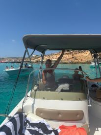 A woman enjoys a sunny day on a boat, capturing the essence of summer fun and relaxation in crystal-clear waters.