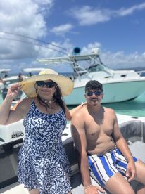 A joyful moment captured on a boat, featuring a woman and a young man enjoying a sunny day on the water — perfect for family outings and summer adventures.