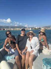 A cheerful group enjoys a sunny day on a boat, capturing memories against a beautiful coastal backdrop — perfect for family outings or celebrations.
