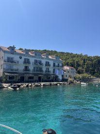 A picturesque view of the Royal Hotel along a stunning coastline, with clear turquoise waters inviting guests to enjoy a relaxing day by the sea.