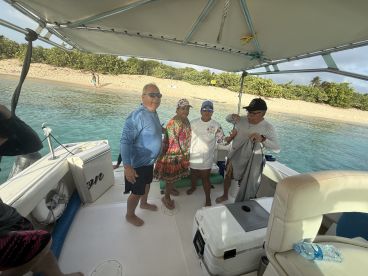 A cheerful group of friends enjoys their time aboard a boat, with a beautiful beach backdrop — perfect for memorable outings and adventures on the water.