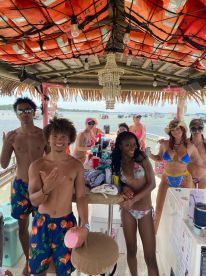 A lively group of friends enjoys a fun day on the water, celebrating together on a boat with drinks and laughter.