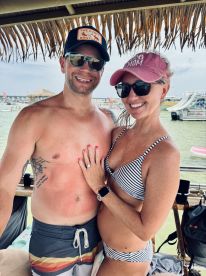 A happy couple poses together at a beachside location, showcasing their joy and love in a sunny setting — perfect for romantic getaways or celebrations.