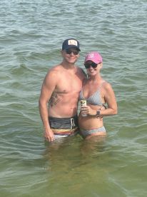 A happy couple enjoys a refreshing swim in shallow waters, perfect for a fun day at the beach.