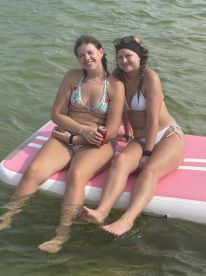 Two friends enjoy a sunny day on a floating mat in the water, capturing the essence of summer fun and relaxation.