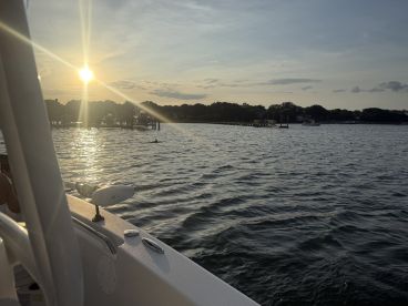 A beautiful sunset view from a boat, showcasing the shimmering water and a nearby dock — perfect for capturing serene moments on the water.