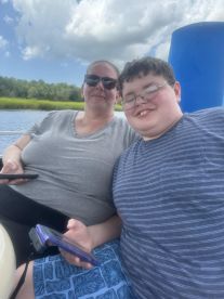 A mother and her son relax on a boat, enjoying their time together while capturing the moment with their phones — perfect for family outings on the water.