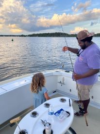 A joyful moment on the water as a man shows a child their catch while fishing from a boat — a perfect family bonding experience on the water.