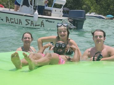 A lively group enjoys a snorkeling adventure in clear waters, showcasing fun and camaraderie with a boat in the background.