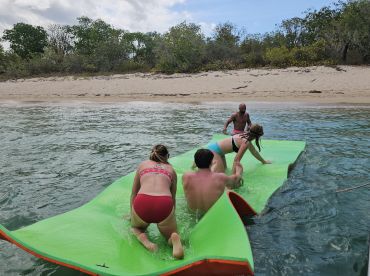 A lively group enjoys a fun day on a floating mat in the water, showcasing the perfect beach activity for friends and family.