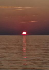 A stunning sunset over calm waters, with vibrant colors reflecting on the surface — a perfect backdrop for evening boat cruises.
