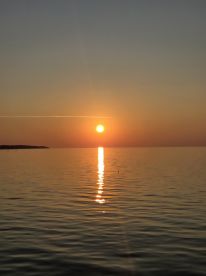 A stunning sunset casts a golden reflection on calm waters, creating a picturesque scene perfect for evening boat trips or romantic getaways.
