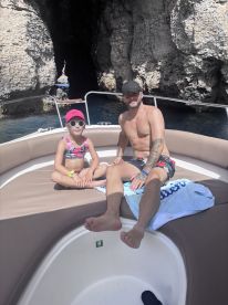 A father and daughter relax on the boat, enjoying a sunny day near a scenic cave — perfect for family adventures on the water.