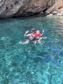 A joyful moment captured as a father and daughter swim together in crystal-clear waters, showcasing the perfect family adventure in a stunning natural setting.
