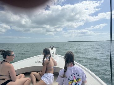 A group of women and a girl enjoy a scenic boat ride, taking in the beautiful ocean views — perfect for family outings and adventures on the water.