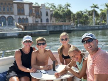 A cheerful family enjoys a sunny day on a boat, capturing memorable moments against a beautiful waterfront backdrop.