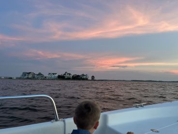 A child gazes at a beautiful sunset over the waterfront, creating a serene backdrop for memorable boating experiences.