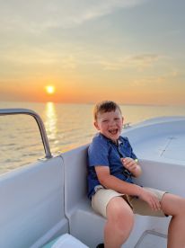 A joyful child enjoys a sunset boat ride, capturing the essence of family fun on the water.