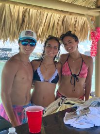 A fun group of friends poses together at a beachside bar, enjoying their time in the sun — perfect for summer celebrations and beach outings.