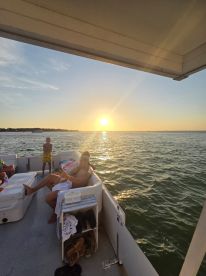 A group enjoys a relaxing evening on a boat as the sun sets over the water, creating a picturesque backdrop for memorable moments.