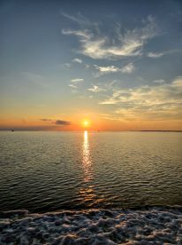 A stunning sunset casts a golden reflection on the calm waters, creating a picturesque scene perfect for evening boat trips or romantic getaways.