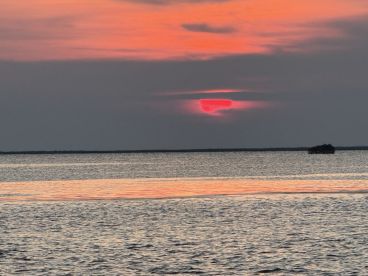 A stunning sunset casts vibrant hues over the water, creating a picturesque scene perfect for evening boat trips or romantic getaways.