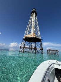 A stunning view of a lighthouse standing tall above crystal-clear waters, showcasing the beauty of the surrounding marine landscape — perfect for sightseeing and photography.