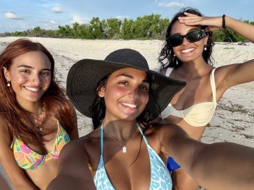 Three friends pose for a cheerful selfie on the beach, capturing a fun moment under the sun — perfect for summer adventures and beach outings.