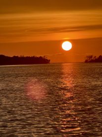 A beautiful sunset reflecting on the water, creating a serene atmosphere. Ideal for capturing the tranquility of nature.