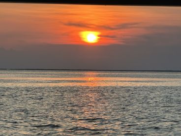 A serene sunset over calm waters, providing a picturesque backdrop for evening boat cruises and relaxation on the water.