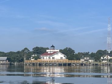 A scenic view of a waterfront building with a lighthouse, reflecting in calm waters. The image lacks clarity and detail.