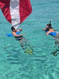 Two individuals enjoy snorkeling in crystal-clear waters, showcasing the perfect tropical adventure.