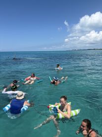 A lively group enjoys a fun day in the water, floating and swimming in the clear turquoise sea — perfect for summer adventures and beach outings.
