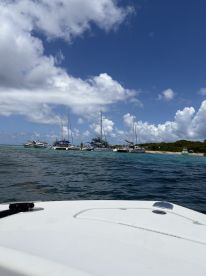 A picturesque view of sailboats anchored near a tropical island, showcasing the serene beauty of the coastline under a bright blue sky.