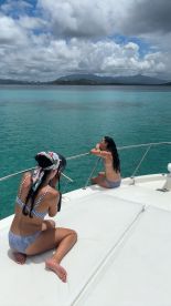 Two friends enjoy a sunny day on a boat, capturing memories against a stunning ocean backdrop — perfect for summer adventures and photography sessions.