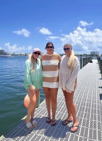 Three friends pose for a cheerful photo on the dock, enjoying a sunny day by the water — perfect for capturing memories of summer adventures.
