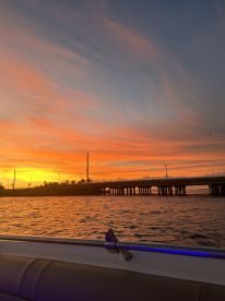 A stunning sunset view from the deck of a boat, showcasing vibrant colors reflecting on the water — perfect for evening cruises.