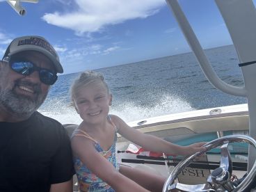 A joyful moment captured as a father and daughter enjoy a boat ride together, showcasing family fun on the open water.