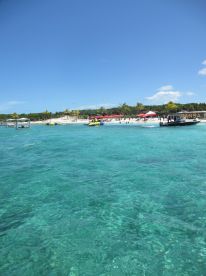 A vibrant beach scene featuring turquoise waters and various water activities, perfect for a fun day in the sun.